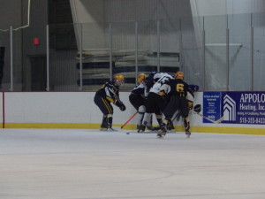Saratoga's Nick Conchieri '14 (#13) scuffles for the puck as Queensbury's Ben Willows '15 (#25) looks on.